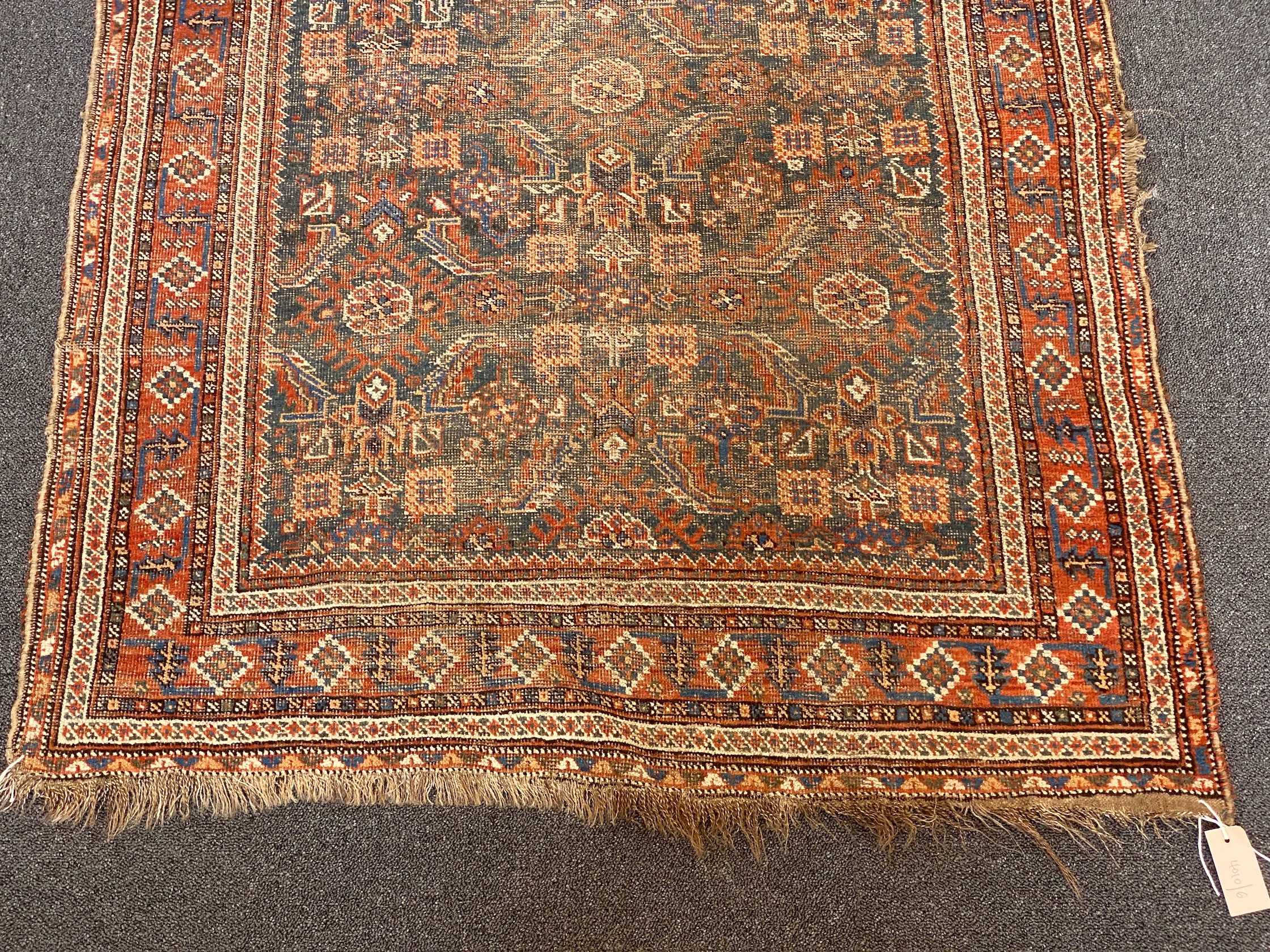 A Shiraz blue ground rug with dense floral field (worn), 144 x 102 cms